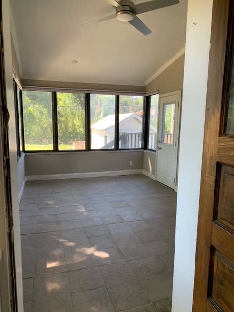 a empty room with a ceiling fan and many windows