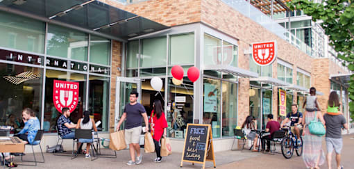 A group of people are outside of a United International store.