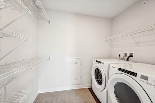 a washer and dryer in a laundry room with white walls and white shelves
