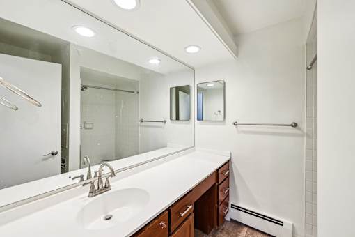 A bathroom with a sink, mirror, and shower.