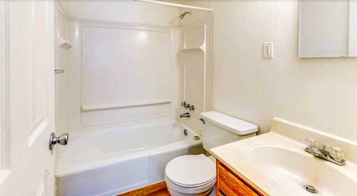 A white bathroom with a toilet, sink, and bathtub.