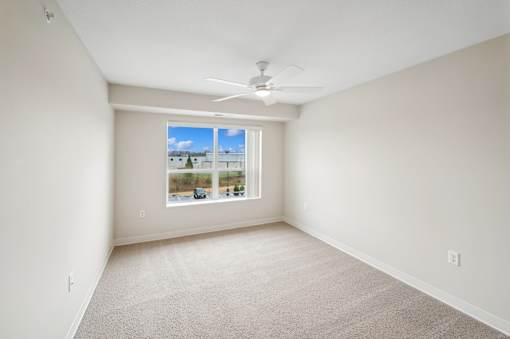 an empty room with a window and a ceiling fan