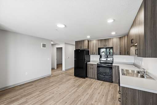 A modern kitchen with wooden cabinets and a black refrigerator.