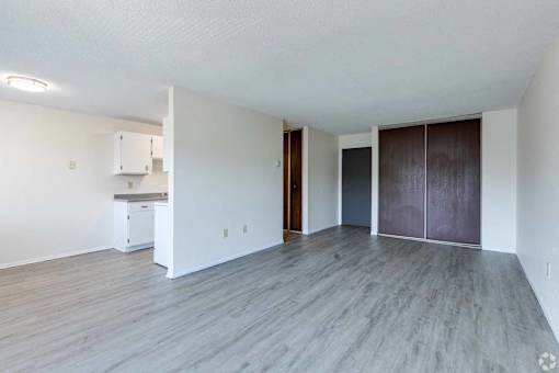 A spacious room with wooden flooring and white walls.