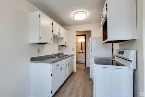 A kitchen with white cabinets and appliances.