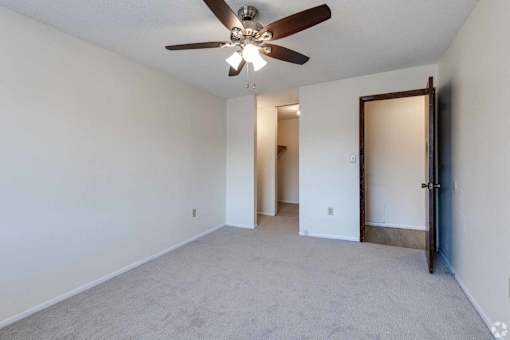 A room with a ceiling fan and carpeted floor.