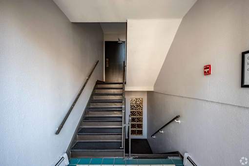 A staircase with a metal railing and steps leading to a door.