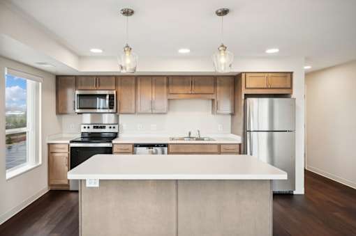an empty kitchen with a white island and stainless steel appliances