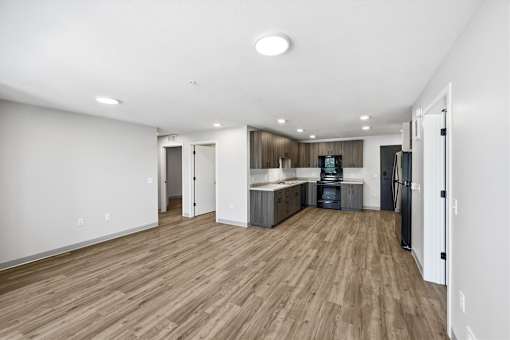 A spacious kitchen with wooden floors and white walls.