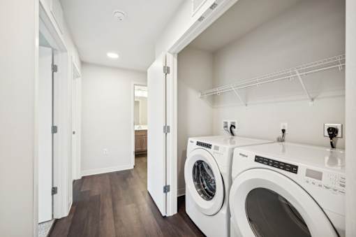 a washer and dryer in a laundry room with white walls and wood floors