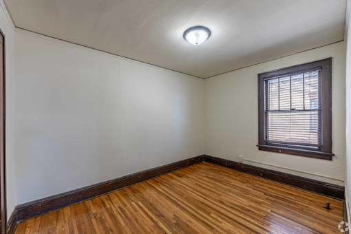 A room with wooden floors and a window with blinds.