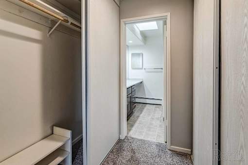 a hallway with a closet and a bathroom with a sink and a mirror