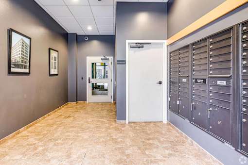A hallway with a white door and a wall of mailboxes.