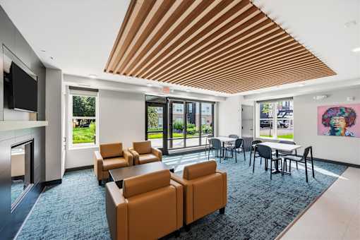 A modern office lounge with orange chairs and a wooden ceiling.