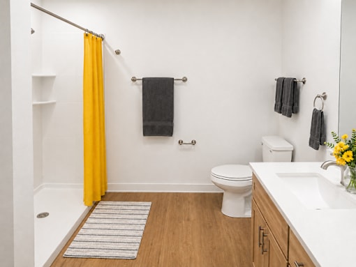 A bathroom with a toilet, sink, and yellow shower curtain.
