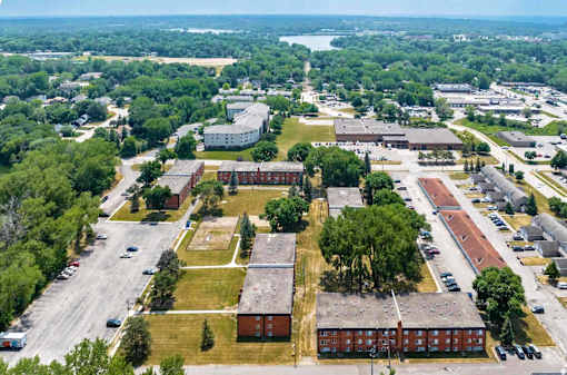 A bird's eye view of a campus with buildings, trees, and a parking lot.
