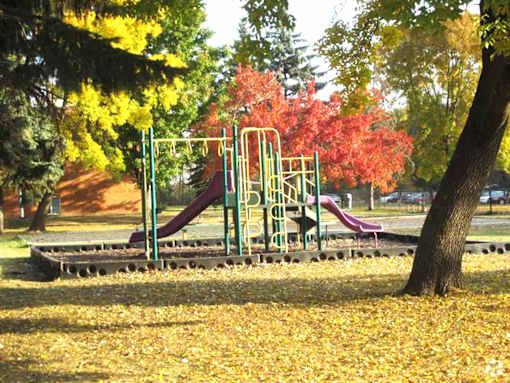A playground with a green slide and a red slide.