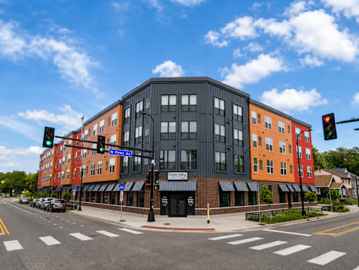 A street view of a multi-story building with a black facade and a red facade on the side.