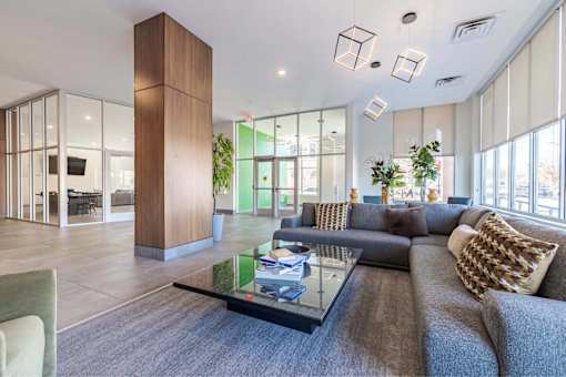 A modern living room with a grey couch and a glass coffee table.