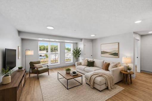 A modern living room with a large window, a sofa, a coffee table, and a TV.