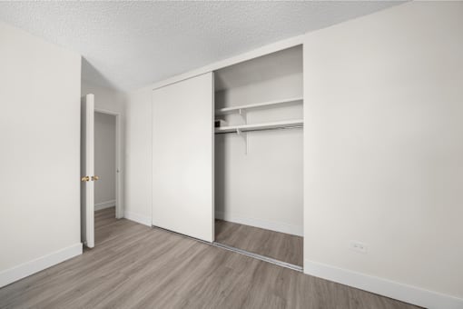 A room with a white door and a closet with shelves.