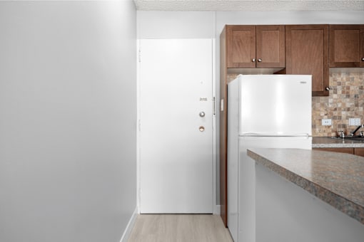 A white fridge in a kitchen with wooden cabinets.