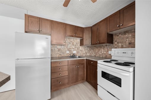 A kitchen with a white refrigerator, white stove, and brown cabinets.