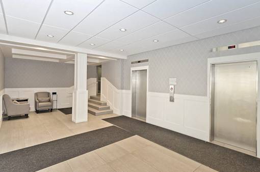 A hallway with a staircase and two elevators.