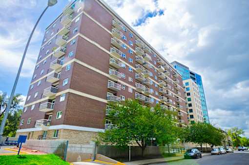 A tall apartment building with a blue sky and clouds in the background.