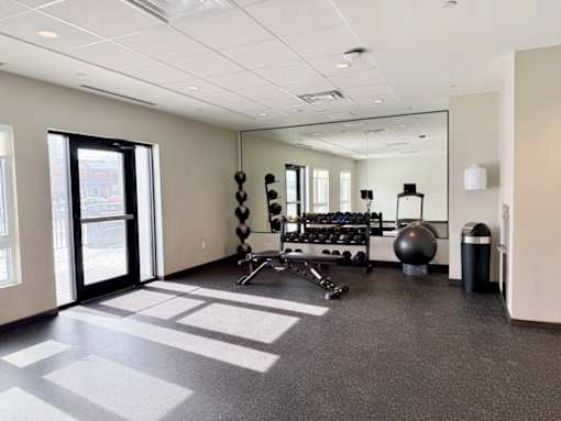 A spacious gym with a variety of equipment including dumbbells, a medicine ball, and a jump rope.