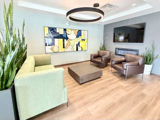 A living room with a green couch, brown leather couch, and a TV mounted on the wall.