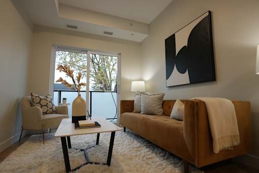 A living room with a brown couch, a white coffee table, and a large painting on the wall.