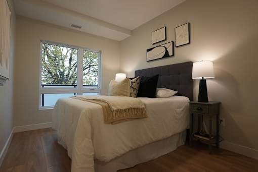 A bedroom with a bed, nightstand, and a window.