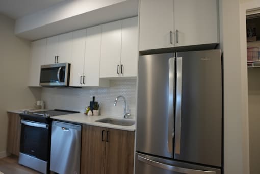 A modern kitchen with a stainless steel refrigerator and microwave above the oven.