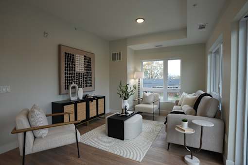 A living room with a large painting on the wall and a white rug on the floor.