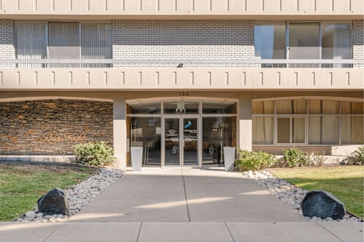The entrance to a building with a stone wall and glass doors.