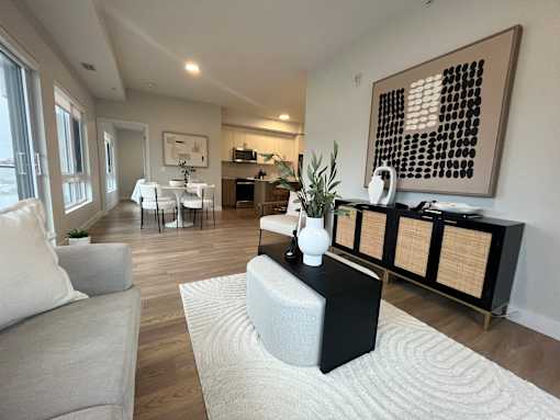 A modern living room with a grey sofa, a white coffee table, and a large abstract painting on the wall.