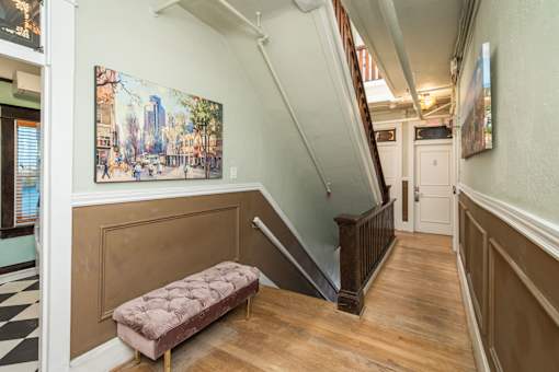 A staircase with a bench and a painting on the wall.