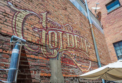 The Old Shoe's sign is on a brick wall.