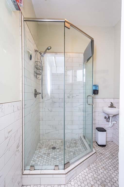A white tiled bathroom with a walk in shower.