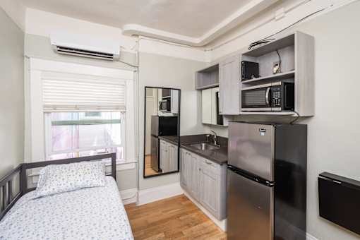 A small kitchen with a bed in the corner.