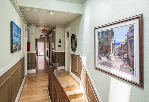 A hallway with a staircase and a painting on the wall.