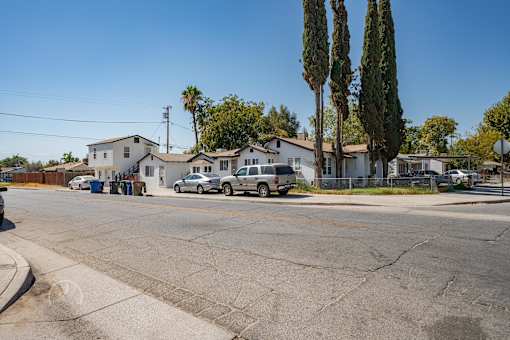 A street view with cars parked and houses in the background.