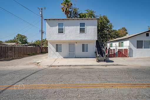 A white two-story house with a wooden fence in front.