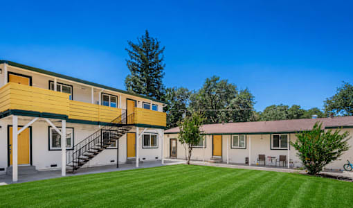 A yellow and white building with a green lawn in front.