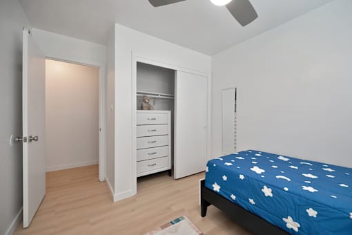 A bedroom with a bed, dresser, and wardrobe.