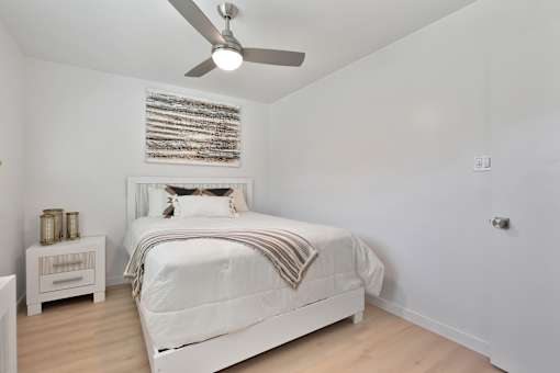 A white bedroom with a large bed and a ceiling fan.