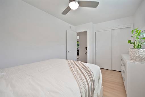 A bedroom with a bed, a ceiling fan, and a cabinet.