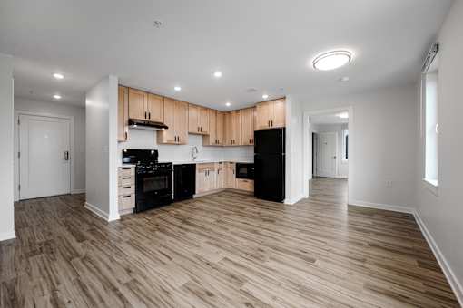 A kitchen with wooden floors and black appliances.