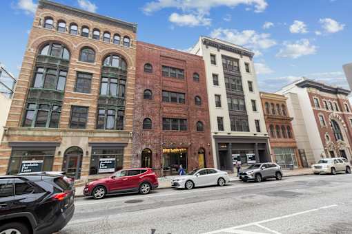 A row of buildings with cars parked in front.